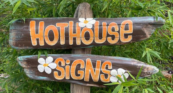 Wooden sign with 'Hothouse Signs' text and flower designs on a green leafy background